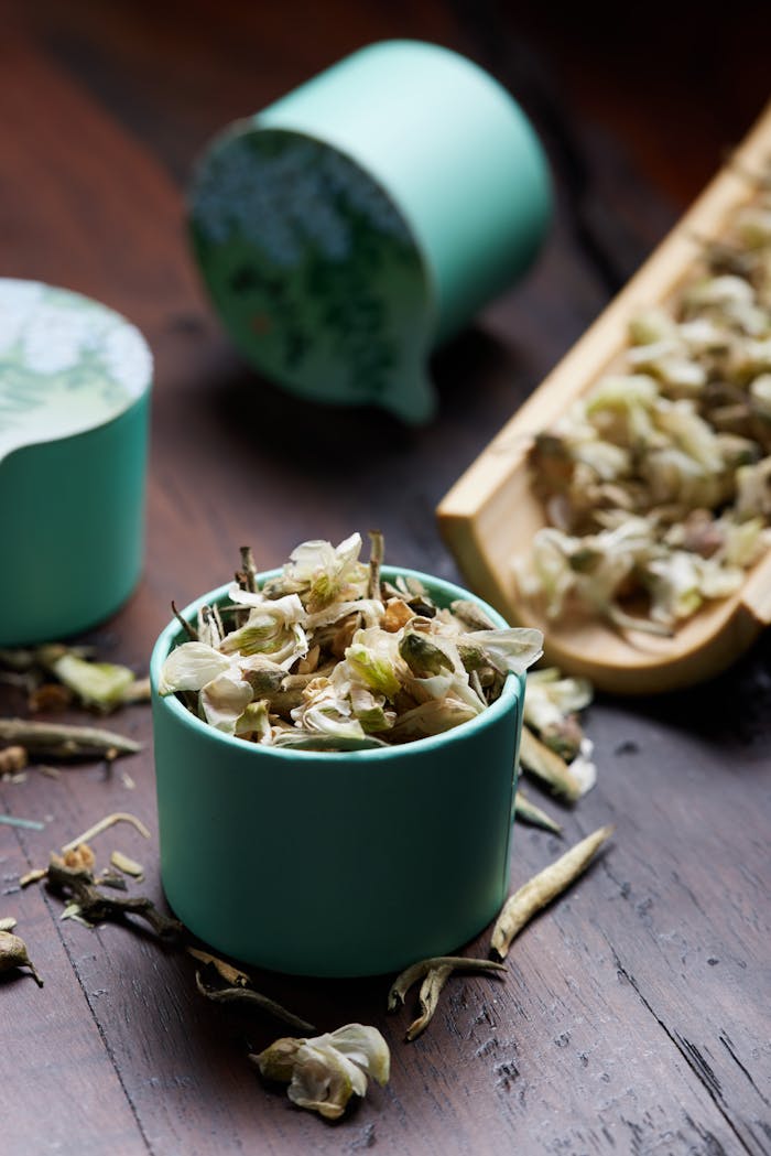 who-we-are Close-up of dried herbs and leaves in a green cup on a wooden surface.