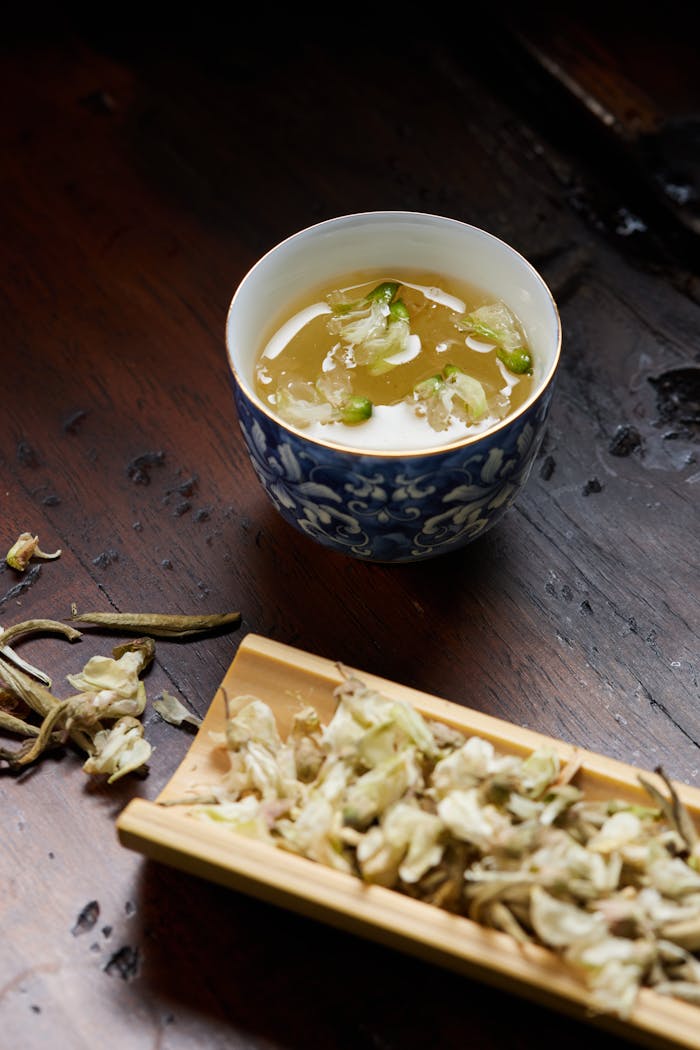 services-02 Beautifully presented Chinese tea in a floral blue cup with dried flowers.