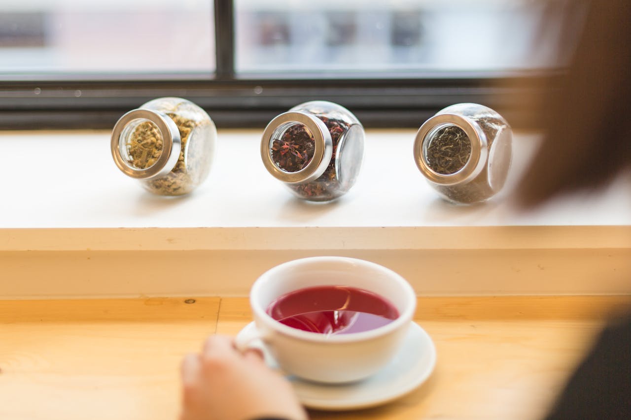 services-01 A warm cup of herbal tea with assorted dried herbs in glass jars, creating a cozy and healthy ambiance.